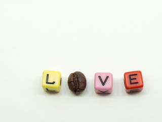 A cluster of thin coffee beans on light wood floor. There is a love letter. Consisting of letters and coffee