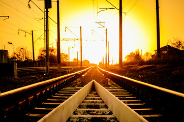 Obraz na płótnie Canvas Railway - Railroad at sunset with sun, Rails and electric lines in yellow light