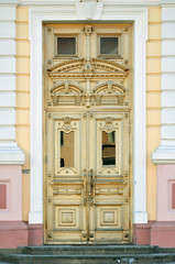 Old yellow vintage door of an historic building with carved wooden decoration. Grodno, Belarus.