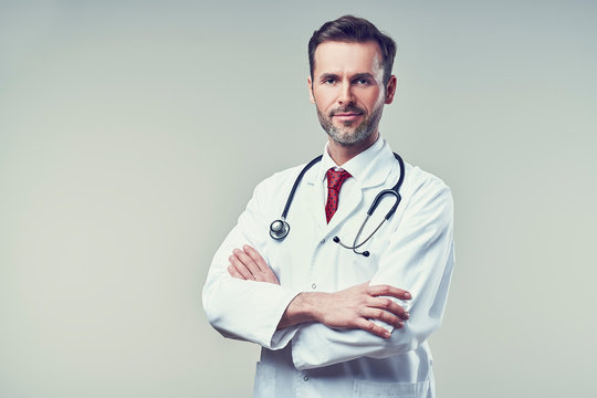 Portrait of handsome doctor standing with crossed arms. Isolated