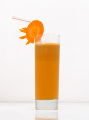 carrot juice in a glass with a straw and a slice of carrot. drink isolated on white background