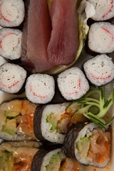 Assorted sushi set served in white box against white background