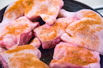 Juicy chicken pieces with spices are fried in a pan in oil on the stove
