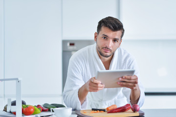 Happy man using digital tablet in kitchen at home