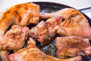 Juicy chicken pieces with spices are fried in a pan in oil on the stove
