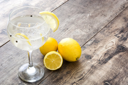 Glass of gin tonic with lemon on wooden background
