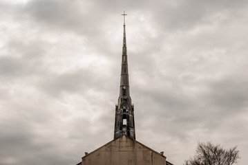 Church steel brass spire. Church building roof with spire and holy cross. Cloudy moody sky background. Minimal architecture design and detail. Exterior design and detail. Abstract architecture. 