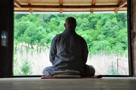 Buddhist Meditation. Older Man Meditating In A Wooden House. Senior Man Practicing Meditation And Looking The Nature