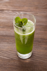Smoothies green dietary vegetarian on a wooden table with mint leaf