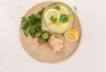 A glass decanter with a summer refreshing lemonade made of lemons and ginger with mint added on a...