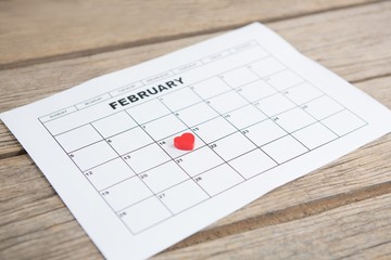 Red heart shape placed on 14th February date of the calendar