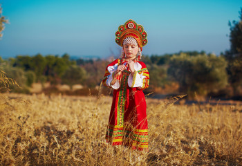 Russian beauty girl in traditional folk costume in field