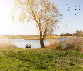 Obraz premium men sitting on the shore of the lake