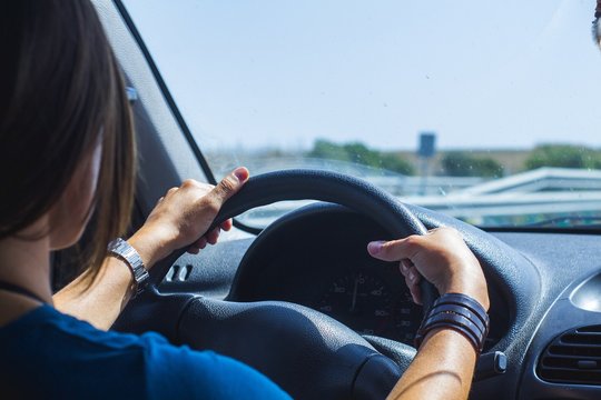 Mujer conduciendo con las manos en el volante.