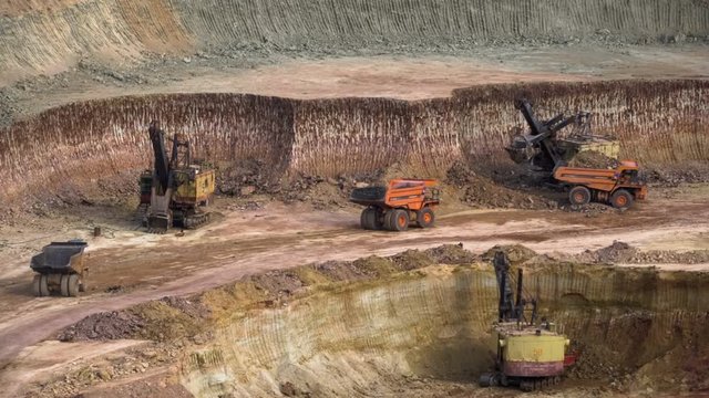 Excavators load ore into dump-trucks. This area has been mined for buaxite, aluminum and other minerals. Open-cast. Operating mine. Bauxite quarry.