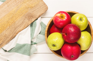 Red and green apples on a white wooden background, horizontal, soft focus, top view
