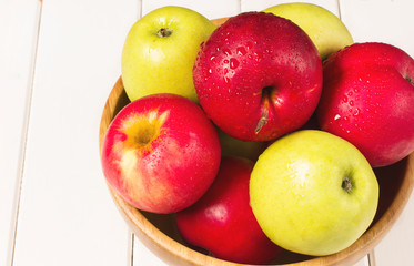 Red and green apples on a white wooden background, horizontal, soft focus, top view
