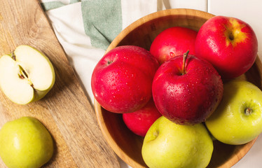 Red and green apples on a white wooden background, horizontal, soft focus, top view
