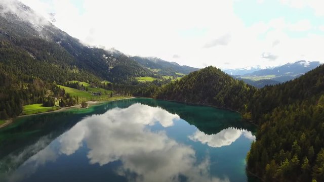 Aerial: flying over Hintersteiner Mountain lake with clear water in Austria and beautiful cloud reflections