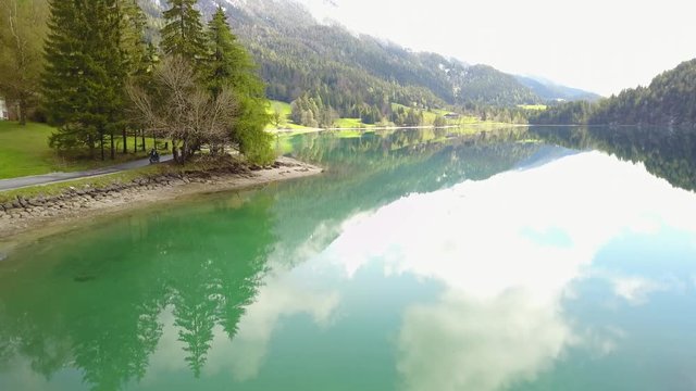 Aerial: flying over Hintersteiner Mountain lake with clear water in Austria and beautiful cloud reflections