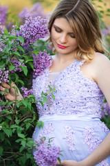 Pretty pregnant girl in blossom lilac garden