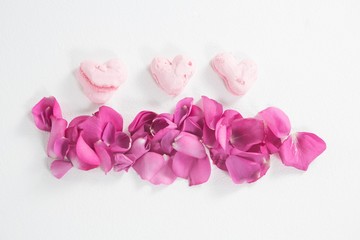 Obraz na płótnie Canvas Heart shaped confectionery and pink rose petals