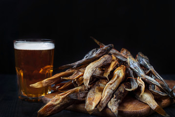 A glass of beer with dried fish. Light beer with sea Bullhead. Goby and beer on a dark background