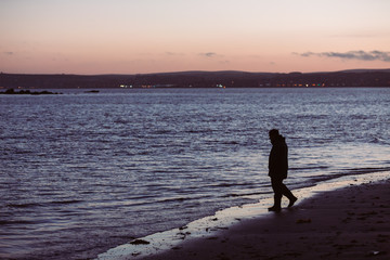Man walking on beach at night looking into the sea with desire