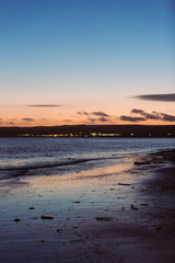Fototapeta na wymiar Sunset on beach with citylights