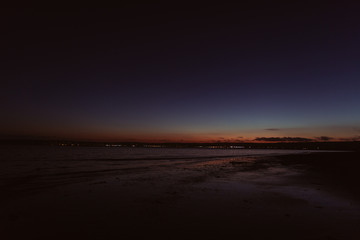 Sunset on beach with citylights