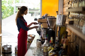 Waitress making cup of coffee at counter