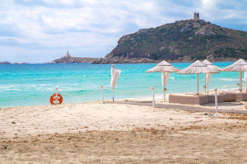 Sunbeds with umbrellas on white sand beach in Villasimius beach, Sardinia island, Italy