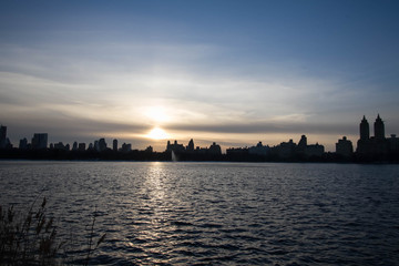 Fototapeta na wymiar Sunset over silhouette buildings and lake with blue sky, Manhattan