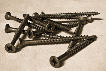 Iron bronzed screws on a wooden table. Still-life picture taken in studio.