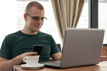 Young man with glasses looks at the laptop and surf the internet
