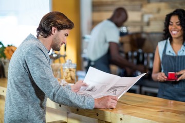 Man reading newspaper at counter