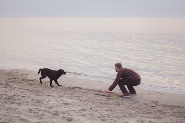 young caucasian male play with dog on the beach