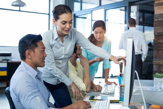 Graphic designers interacting while working on personal computer