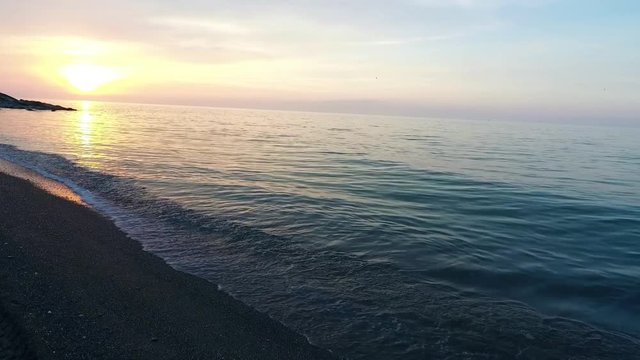 Waves gently wash up onto the beach, then recede as the sunset. A beautiful sunset over a sea Akcakoca in Turkey