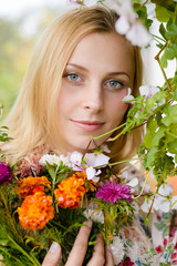 Close up portrait of beautiful blond young woman pretty girl standing under blooming tree