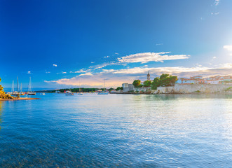 Fototapeta na wymiar Wonderful romantic summer evening landscape panorama coastline Adriatic sea. Boats and yachts in harbor at cristal clear azure water. Old town of Krk on the island of Krk. Croatia. Europe.