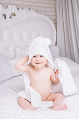 Adorably baby lie on white towel in bed. Happy childhood and healthcare concept.