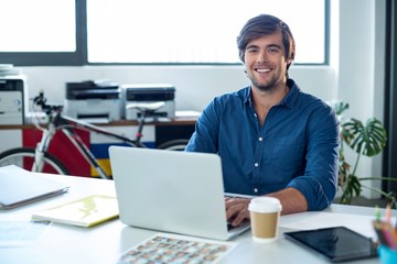 Portrait of male graphic designer working on laptop