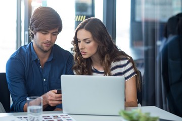 Male and female business executive using mobile phone