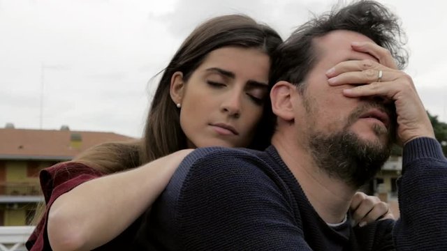 Woman hugging strong sad man medium shot