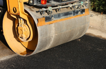 detail of a road roller with the black asphalt of a street
