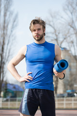 Fototapeta premium muscular man holding yoga or fitness mat for exercise