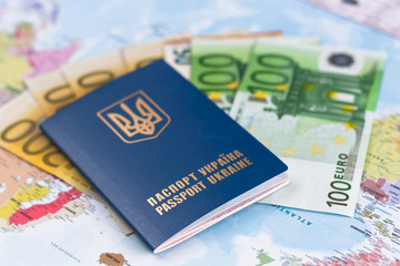 Ukranian travel passport laying  on different euro banknotes,  world map on the  background.
