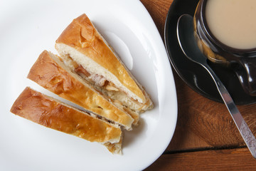 Fresh homemade apple pie and tea with milk on a wooden background