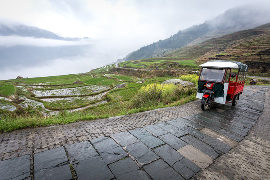 un petit véhicule à moteur sur une route de montagne au milieu des terrasses de rizières